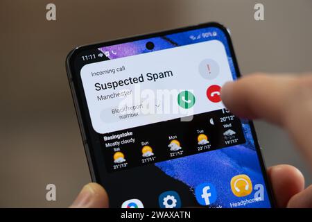 Eine Person, die kurz davor steht, bei einem eingehenden Anruf aufzulegen, der von einem Android-Smartphone in Großbritannien als „vermuteter Spam“ aufgeführt wird. Thema: Spam-Anrufe, betrügerischer Anruf, ICO Stockfoto