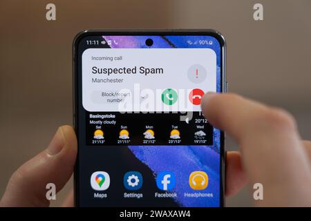 Eine Person, die kurz davor steht, bei einem eingehenden Anruf aufzulegen, der von einem Android-Smartphone in Großbritannien als „vermuteter Spam“ aufgeführt wird. Thema: Spam-Anrufe, betrügerischer Anruf, ICO Stockfoto