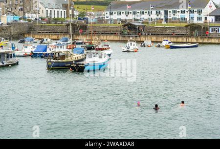 Porthleven, Großbritannien - 25. Juni 2022: Kaltwasserschwimmer trotzen dem kalten Meer im Hafen von Porthleven Stockfoto