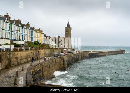 Porthleven, Großbritannien – Juni 2022: Stürmisches Meer am Hafen von Porthleven. In der Ferne befindet sich der Uhrturm des Bickford-Smith Scientific and Literary Institute Stockfoto