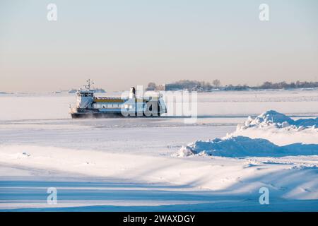 Helsinki / Finnland - 7. JANUAR 2024: Eine wunderschöne winterliche Szene aus Helsinki. Eine Fähre, die von Sunlines betrieben wird und durch die Inseln fährt Stockfoto