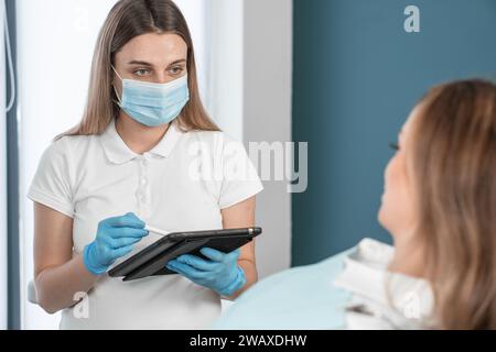 Eine Zahnärztin, die durch ihre Professionalität und Entschlossenheit beeindruckt, betreut ihre Patienten in einer gemütlichen Zahnarztpraxis. Ihre Sorgfalt und Aufmerksamkeit Stockfoto