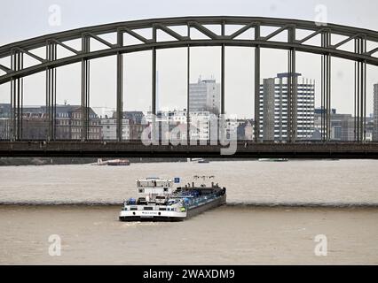 Köln, Deutschland. Januar 2024. Ein Schiff überquert die Hohenzollernbrücke auf dem Rhein. Trotz sinkender Wasserstände können nur Schiffe mit flachem Boden den Fluss befahren, da nur sie bei Hochwasser unter den Brücken passieren können. Quelle: Roberto Pfeil/dpa/Alamy Live News Stockfoto