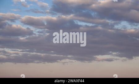 Das Bild zeigt flauschige Wolken vor einem weichen blauen Himmel während des Sonnenuntergangs. Stockfoto