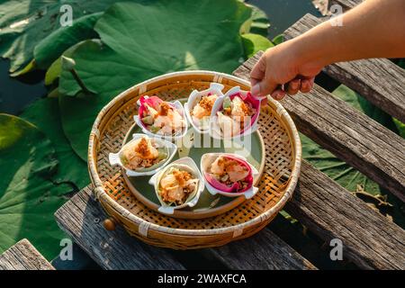 Traditioneller thailändischer Snack namens Miang Kham, pikant rosa Lotusblüten verpackt (pikante Lotusblüten-Wraps). Köstliches Frisches Lotusblüten-Bohnenkraut Stockfoto