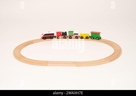 Spielzeugzugwagen auf der Bahn, weißer Hintergrund im Studio. Kinder trainieren auf einer Holzbahn Stockfoto