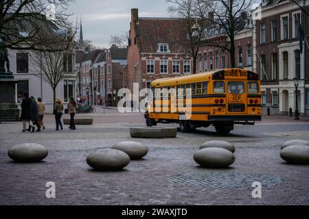 Domplein 9, 3512 JC Utrecht, Niederlande - 27. Dezember 2023: Amerikanischer Schulbus zwischen Dom Tower und St. Martin's Cathedral. Stockfoto