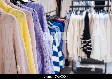 Farbenfrohe Damenkleidung an Kleiderbügeln in einem Einzelhandelsgeschäft. Mode- und Einkaufskonzept Stockfoto