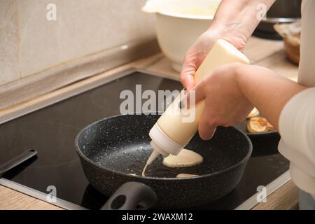 Frau, die kondensierten Teig in die Pfanne in der Küche gießt, Nahansicht Stockfoto