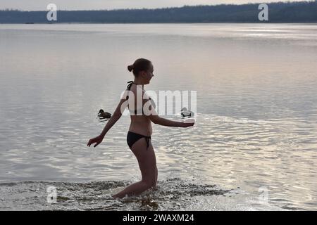 Eine Frau bereitet sich darauf vor, während der Epiphanienfeier in kaltes Wasser des Flusses Dnipro zu tauchen. Erstmals seit 1917 wird am 6. Januar die Epiphanie gefeiert, die das traditionelle Datum des 19. Januar ersetzt. Die Ukraine hat traditionell den Julianischen Kalender verwendet, der auch von Russland verwendet wird, wo Epiphanien am 19. Januar fällt. In einem weiteren Wechsel von Russland markiert es nun die Epiphanik nach dem westlichen - oder gregorianischen - Kalender. Epiphanik ist einer der wichtigsten religiösen Feiertage im orthodoxen Kalender. Stockfoto