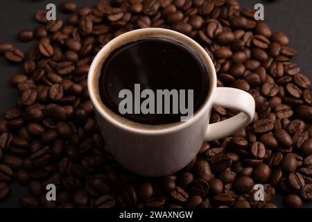 Auf diesem Nahaufnahme-Foto wird eine Tasse Espresso durch strukturierte Kaffeebohnen zu einer visuellen Symphonie aus Energie und Koffein. Die reichhaltige Textur der Bohnen inv Stockfoto
