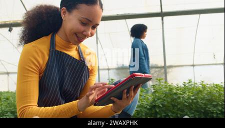 Nahaufnahme von jungen, multiethnischen Landwirten mit digitalem Tablet, Gewächshaus Stockfoto