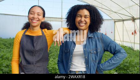 Porträt zweier Farmerinnen, die lächelnd und lachend im Gewächshaus stehen Stockfoto