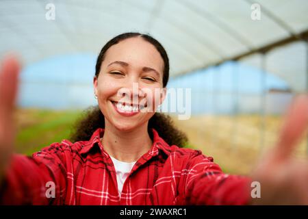 Multiethnische Farmerin, die Selfie mit Gewächshaus im Hintergrund macht Stockfoto