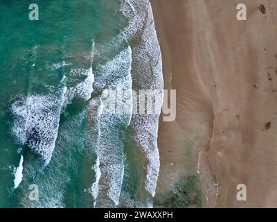 Eine ruhige Strandszene mit großen Wellen, die auf eine felsige Küste stürzen Stockfoto