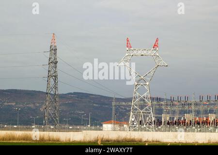 Großer Elektromast mit noch nicht verbundenen Stahlkabeln ist zusammen mit dem Kraftwerk auf dem Land Stockfoto