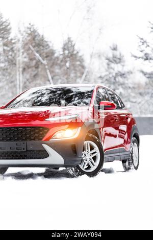 Ein moderner roter Geländewagen mit Allradantrieb steht am Rande einer Winterstraße. Nahaufnahme eines Autos auf einer verschneiten Winterstraße. Familienreisekonzept zum Skifahren Stockfoto