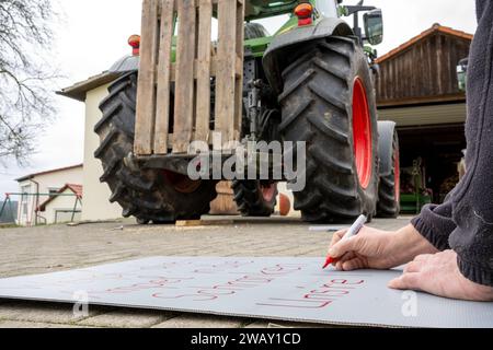 07. Januar 2024, Bayern, Wüstenwelsberg: Ein Mann schreibt ein Protestzeichen für einen Schlepper. Die Landwirte bereiten sich auf die kommende Aktionswoche vor. Tausende von Landwirten wollen gegen die Agrarpolitik demonstrieren. Foto: Pia Bayer/dpa Stockfoto