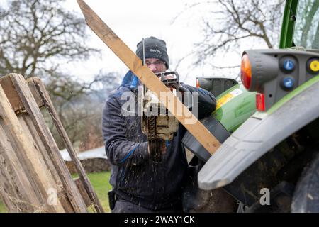 07. Januar 2024, Bayern, Wüstenwelsberg: Ein Mann sägt eine Holzleiste in Form, damit er ein Protestzeichen an seinem Traktor anbringen kann. Die Landwirte bereiten sich auf die kommende Aktionswoche vor. Tausende von Landwirten wollen gegen die Agrarpolitik demonstrieren. Foto: Pia Bayer/dpa Stockfoto