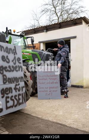 07. Januar 2024, Bayern, Wüstenwelsberg: Ein Landwirt füllt seinen Traktor mit Diesel, hält ein Poster in der linken Hand. Die Bauern bereiten sich auf die kommende Woche der Proteste vor. Tausende von Landwirten wollen gegen die Agrarpolitik demonstrieren. Foto: Pia Bayer/dpa Stockfoto