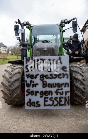 07. Januar 2024, Bayern, Wüstenwelsberg: Ein Landwirt füllt seinen Traktor mit Diesel, um sich auf die kommende Protestwoche vorzubereiten - ein Schild mit der Aufschrift „Niemand sollte jemals vergessen. Wir Landwirte liefern die Nahrung." Tausende von Landwirten wollen gegen die Agrarpolitik demonstrieren. Foto: Pia Bayer/dpa Stockfoto