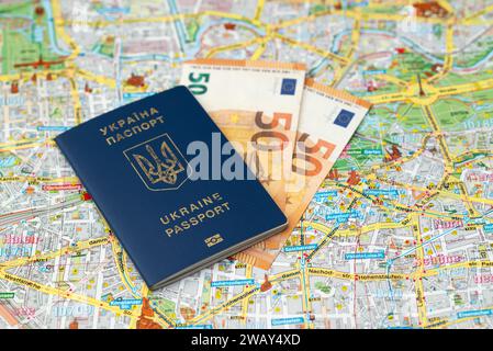 Euro-Banknoten Geld mit ukrainischem Reisepass auf einem Berliner Stadtplan Hintergrund. Stockfoto