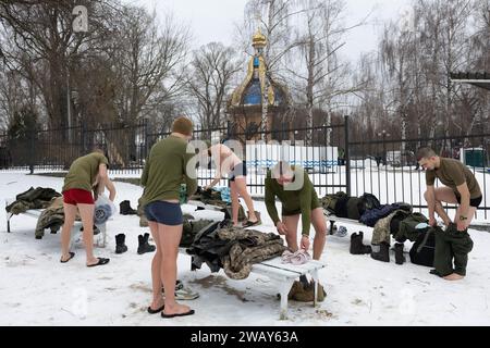 Ukrainische Armeesoldaten ziehen sich an, nachdem sie in den kalten Gewässern des Dnipro-Flusses anlässlich der Feier der Epiphanik in Kiew geschwommen sind. Die Ukraine feiert in diesem Jahr erstmals die Epiphanik am 6. Januar nach dem westlichen Kalender und weicht von der Tradition der russisch-orthodoxen Kirche ab, sie am 19. Januar zu feiern. Während der Epiphanienzeit glauben manche, dass das Wasser besondere heilende Eigenschaften hat und zur Behandlung verschiedener Krankheiten verwendet werden kann, und viele von ihnen nehmen im Rahmen der Epiphanienfeier ein Bad im Wasser. Stockfoto