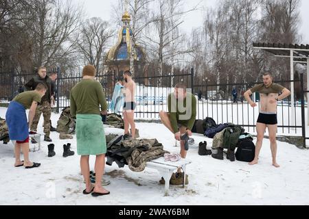 Ukrainische Armeesoldaten ziehen sich an, nachdem sie in den kalten Gewässern des Dnipro-Flusses anlässlich der Feier der Epiphanik in Kiew geschwommen sind. Die Ukraine feiert in diesem Jahr erstmals die Epiphanik am 6. Januar nach dem westlichen Kalender und weicht von der Tradition der russisch-orthodoxen Kirche ab, sie am 19. Januar zu feiern. Während der Epiphanienzeit glauben manche, dass das Wasser besondere heilende Eigenschaften hat und zur Behandlung verschiedener Krankheiten verwendet werden kann, und viele von ihnen nehmen im Rahmen der Epiphanienfeier ein Bad im Wasser. (Foto: Oleksii Chumachenko/SOPA Images/SIPA USA) Stockfoto