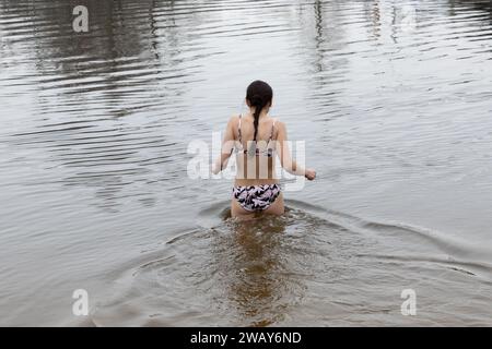 Kiew, Ukraine. Januar 2024. Eine Frau nimmt ein Bad im kalten Wasser des Flusses Dnipro anlässlich der Feier der Epiphanik in Kiew. Die Ukraine feiert in diesem Jahr erstmals die Epiphanik am 6. Januar nach dem westlichen Kalender und weicht von der Tradition der russisch-orthodoxen Kirche ab, sie am 19. Januar zu feiern. Während der Epiphanienzeit glauben manche, dass das Wasser besondere heilende Eigenschaften hat und zur Behandlung verschiedener Krankheiten verwendet werden kann, und viele von ihnen nehmen im Rahmen der Epiphanienfeier ein Bad im Wasser. (Credit Image: © Oleksii Chumachenko/SOPA Images via ZUMA Press Wire Stockfoto