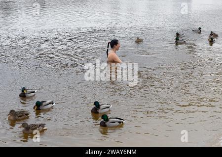 Kiew, Ukraine. Januar 2024. Eine Frau schwimmt neben Enten im kalten Wasser des Dnipro-Flusses anlässlich der Feier des Epiphaniums in Kiew. Die Ukraine feiert in diesem Jahr erstmals die Epiphanik am 6. Januar nach dem westlichen Kalender und weicht von der Tradition der russisch-orthodoxen Kirche ab, sie am 19. Januar zu feiern. Während der Epiphanienzeit glauben manche, dass das Wasser besondere heilende Eigenschaften hat und zur Behandlung verschiedener Krankheiten verwendet werden kann, und viele von ihnen nehmen im Rahmen der Epiphanienfeier ein Bad im Wasser. (Credit Image: © Oleksii Chumachenko/SOPA Images via ZUMA PR Stockfoto