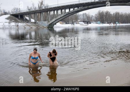 Kiew, Ukraine. Januar 2024. Frauen kommen aus dem Wasser, nachdem sie im kalten Fluss Dnipro geschwommen sind, anlässlich der Feier der Epiphanik in Kiew. Die Ukraine feiert in diesem Jahr erstmals die Epiphanik am 6. Januar nach dem westlichen Kalender und weicht von der Tradition der russisch-orthodoxen Kirche ab, sie am 19. Januar zu feiern. Während der Epiphanienzeit glauben manche, dass das Wasser besondere heilende Eigenschaften hat und zur Behandlung verschiedener Krankheiten verwendet werden kann, und viele von ihnen nehmen im Rahmen der Epiphanienfeier ein Bad im Wasser. (Credit Image: © Oleksii Chumachenko/SOPA images via ZU Stockfoto