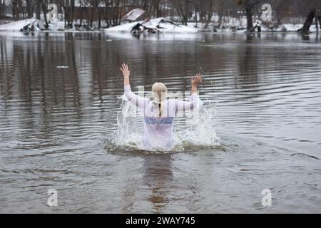 Kiew, Ukraine. Januar 2024. Eine Frau nimmt ein Bad im kalten Wasser des Flusses Dnipro anlässlich der Feier der Epiphanik in Kiew. Die Ukraine feiert in diesem Jahr erstmals die Epiphanik am 6. Januar nach dem westlichen Kalender und weicht von der Tradition der russisch-orthodoxen Kirche ab, sie am 19. Januar zu feiern. Während der Epiphanienzeit glauben manche, dass das Wasser besondere heilende Eigenschaften hat und zur Behandlung verschiedener Krankheiten verwendet werden kann, und viele von ihnen nehmen im Rahmen der Epiphanienfeier ein Bad im Wasser. (Credit Image: © Oleksii Chumachenko/SOPA Images via ZUMA Press Wire Stockfoto