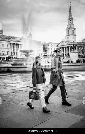 Ein gut gekleidetes junges Paar spaziert durch den Trafalgar Square in London, England, Großbritannien Stockfoto