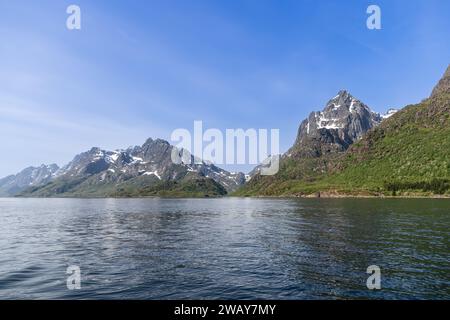 Die majestätischen Berge der Lofoten mit ihren schneebedeckten Spalten ragen majestätisch über den beschaulichen Fjord und verkörpern den ruhigen Geist des natürlichen G Norwegens Stockfoto