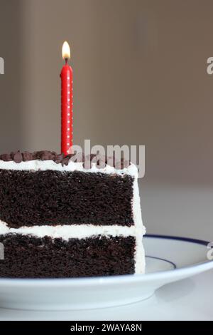 Ein Stück Schokolade Geburtstagskuchen mit rotem Polka Dot Kerze beleuchtet Stockfoto