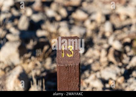Trail Mile Marker Nummer drei (3) auf einen Holzpfosten geschnitzt und gelb bemalt Stockfoto