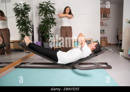 Entspannter Mann, der Yoga-Posen mit dem Lehrer lernt Stockfoto