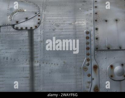 Fragment eines alten Metallrumpfes. Metallischer Hintergrund mit Schrauben und Nieten. Stockfoto