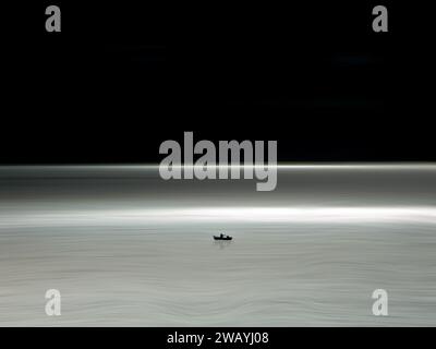 Ein weißes und blaues Boot steht am Rand einer riesigen Fläche von tiefblauem Wasser Stockfoto