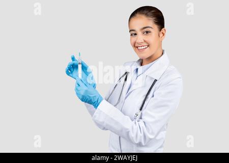 Ein freundlicher kaukasischer Jahrtausendarzt in Labormantel und blauen Handschuhen Stockfoto