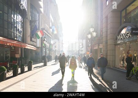 Menschen, die in der Morgensonne auf der Vaci Street in Budapests historischem Stadtzentrum spazieren gehen. Dezember 2023. Stockfoto