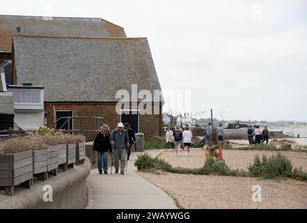 Touristen und Einheimische spazieren entlang des Küstenweges mit traditionellen britischen Häusern in Whitstable kent England. Stockfoto