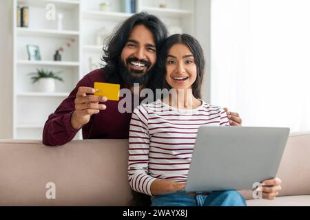 Glückliches, tausendjähriges indisches Paar, das für Waren und Dienstleistungen im Internet bezahlt Stockfoto