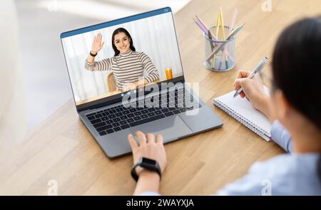 Frau mit Schulterblick hat Videoanruf mit dem Tutor Stockfoto