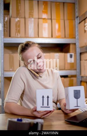 Frau, die ein Mobiltelefon oder Tablet verwendet, um mit Kunden zu kommunizieren. Lieferung von Waren über private Kurierdienste. Konzepte des Online-Verkaufs und Stockfoto