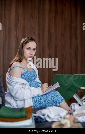 Schwangere Frau Verpackung Tasche für Entbindungskrankenhaus, Notizen machen, Liste im Tagebuch überprüfen. Werdende Mutter mit Koffer mit Babykleidung und Stockfoto