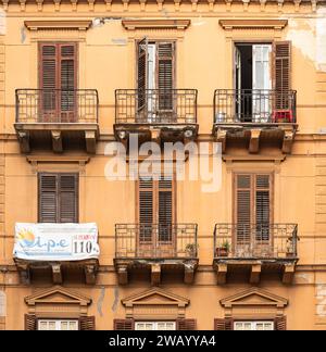 Palermo, Sizilien, Italien, 14. Dezember 2023 - orangefarbene Fassade mit Balkonen und Holzläden in einem traditionellen Wohnblock Stockfoto