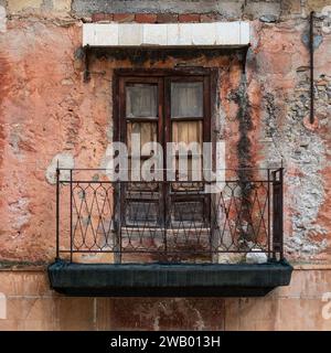 Belmonte - Mezzagno, Sizilien, Italien, 17. Dezember 2023 - Ziegelsteinfassade und Balkon eines abgenutzten Hauses im alten Dorfkern Stockfoto