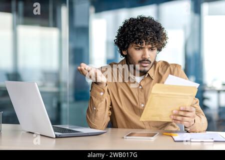Trauriger unzufriedener und unglücklicher Geschäftsmann im Büro am Arbeitsplatz, Mann erhielt Briefumschlag Fuchs mit Benachrichtigung mit schlechten Nachrichten, Arbeiter liest enttäuscht. Stockfoto