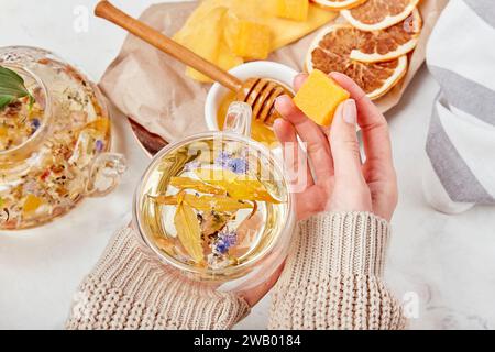 Frau fügen Honig zu Bio-Bergmischung hinzu - beruhigendes Kräuterelixier - Wellness-Retreat mit Kräuteraufgüssen. Stockfoto